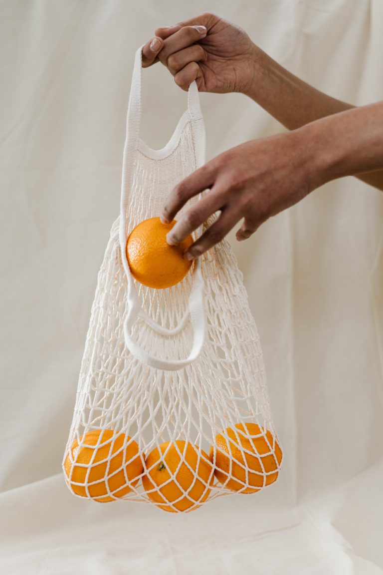 organges in a reusable cotton produce bag to reduce single-use plastic consumption