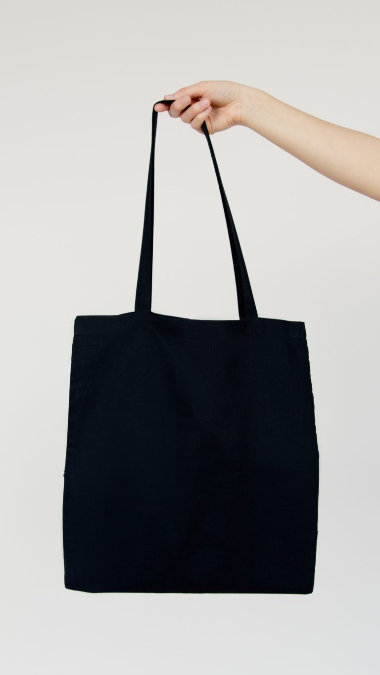 black reusable grocery bag in someone's hand
