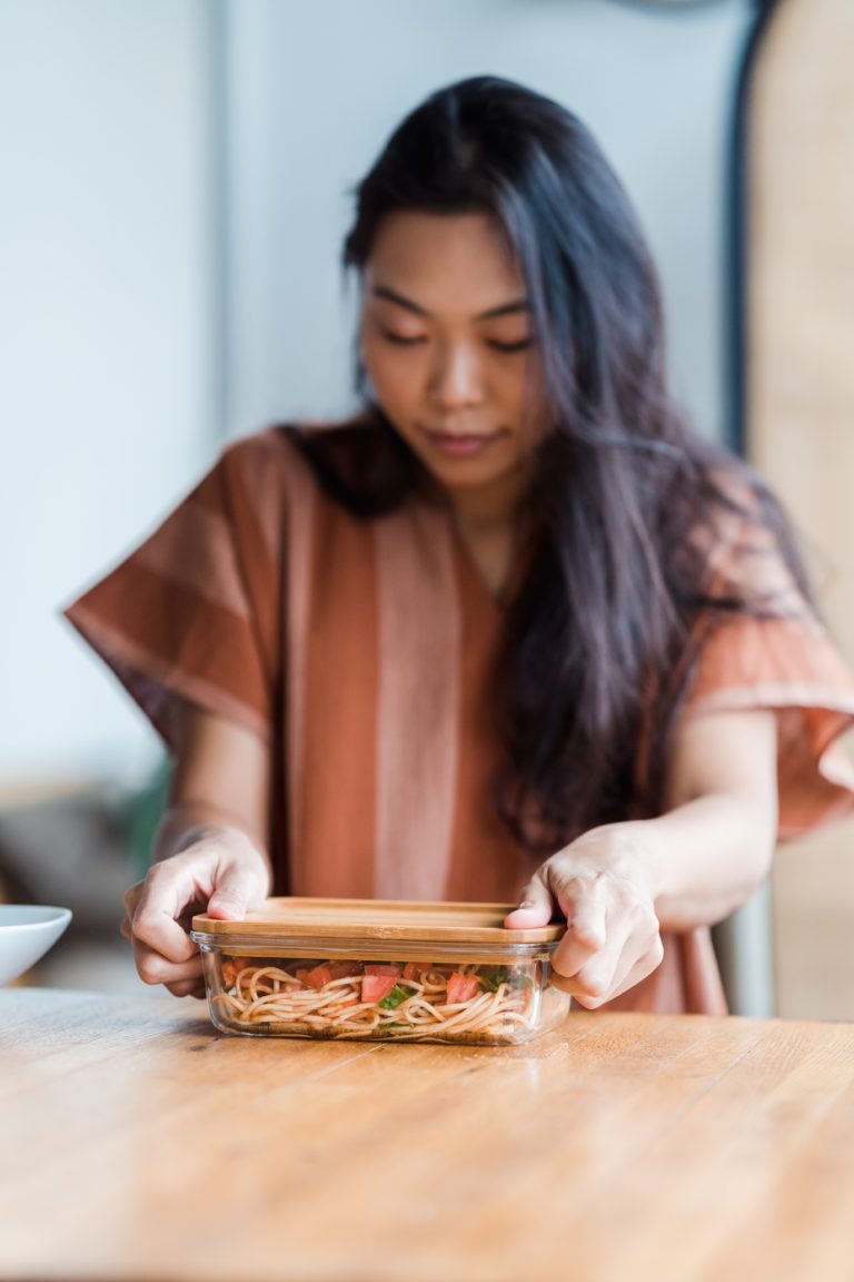 woman storing food in her reusable bamboo and glass food storage container