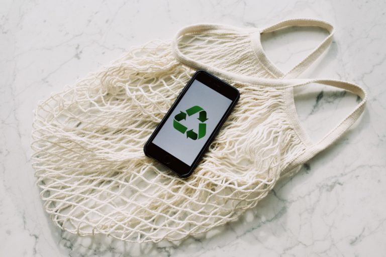 iphone showing recycle symbol on top of cotton reusable produce bag