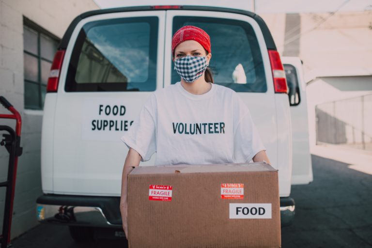 volunteer carrying a box wearing a mask