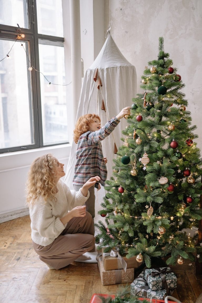 woman and girl decorating christmas tree together