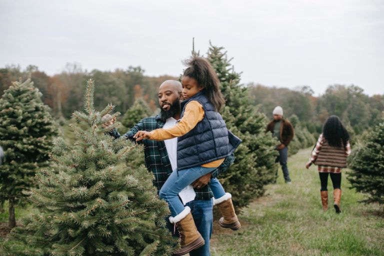 man and girl looking at christmas tree on tree farm