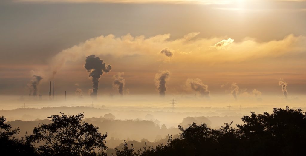 air pollution spewing into the sky in the distance over a sunset