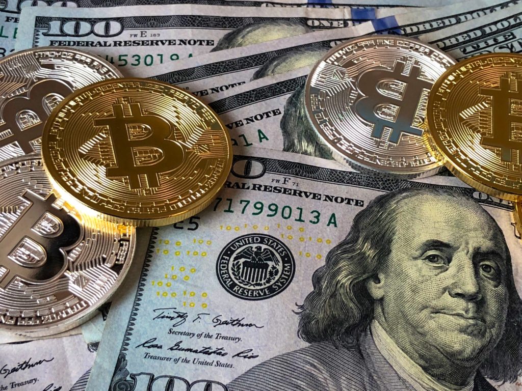 bitcoin and 100 dollar bills representing the economy
