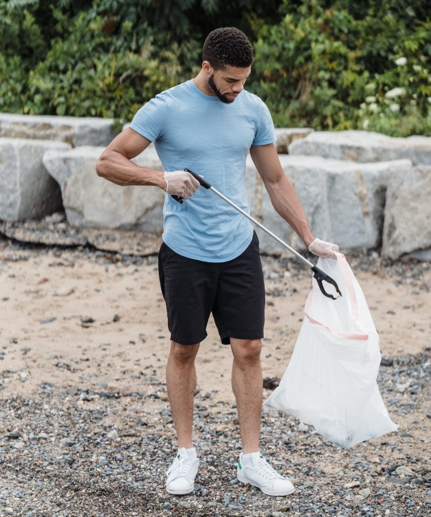 man picking up trash on beach
