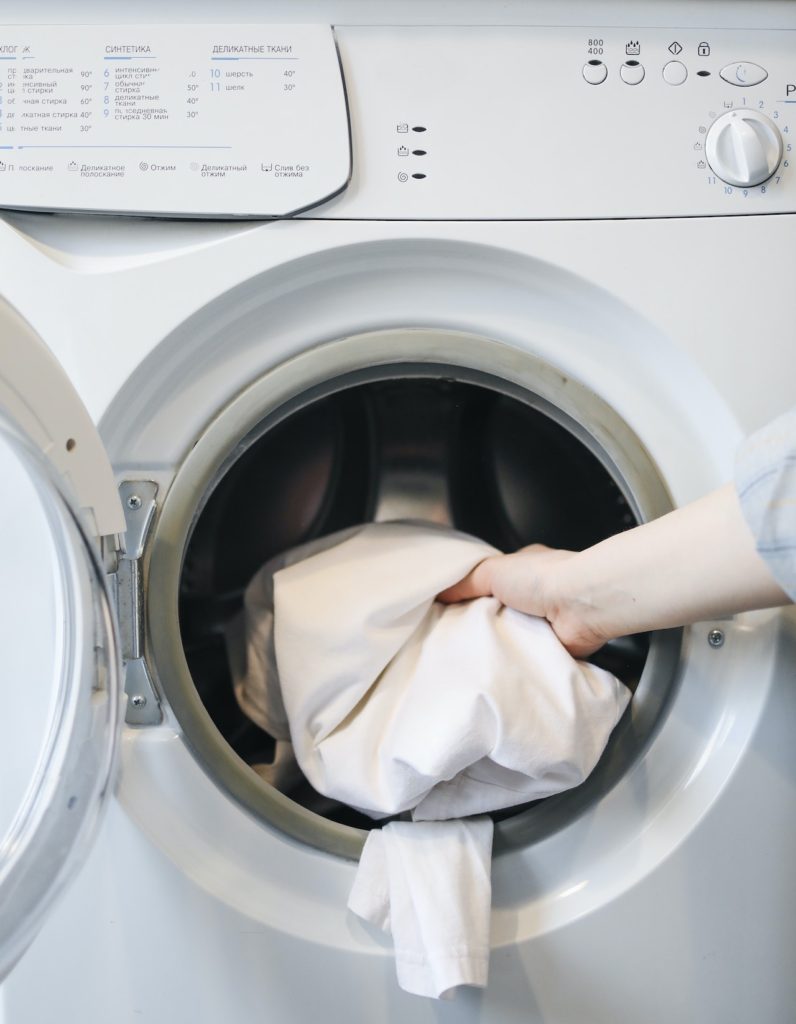 person washing natural fibers in washing machine to avoid microplastics